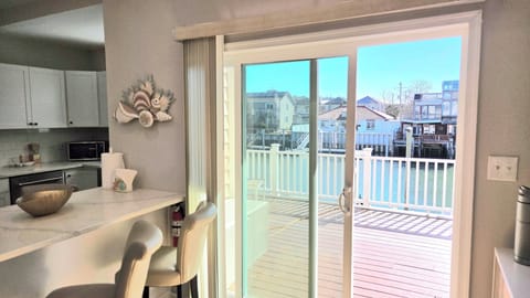 Sunny kitchen and breakfast bar opening to a waterfront deck.