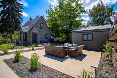 Sunny shared courtyard with wicker lounge set, gravel landscaping, and both bungalows in view — your home base between lake days