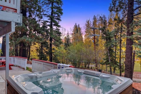 Private hot tub on the deck with serene forest views at sunset.