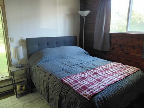 Bedside lamp has alarm clock and USB charging. Window view out to horse pasture.