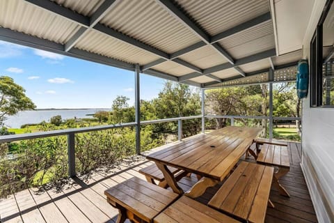 Sheltered and spacious, the deck invites long, relaxed meals at the timber table while overlooking the garden and shimmering water beyond.