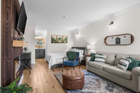 Open-concept studio with King bed, full living space, electric fireplace, and mounted smart TV. Sleeps 4 with the queen sleeper sofa.