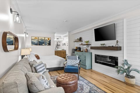 Bright, modern studio with a king bed, full living space, electric fireplace, and mounted smart TV. Sleeps 4 with the queen sleeper sofa.