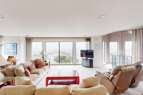 Sink into plush seating in your sunlit living room where panoramic Bodega Bay views stretch beyond floor-to-ceiling windows and a private balcony