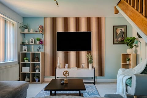 Stylish living room with a bold wood slat feature wall and large smart TV.
