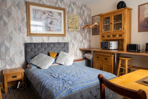 Cosy studio with a velvet double bed, kitchenette, and dining spot all within reach.