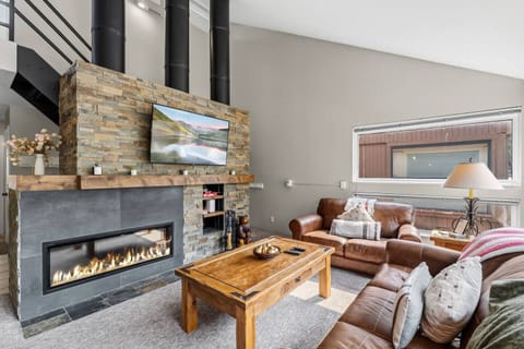 Cozy living room with fireplace and soaring ceilings, framed by stunning Vail mountain views