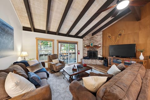 Cozy cabin living room with vaulted ceilings, fireplace, and deck access.