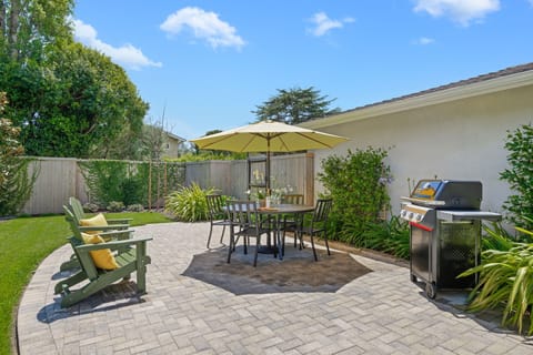 Relax on this beautifully landscaped patio with comfortable seating, perfect for outdoor dining and BBQ gatherings under sunny skies.