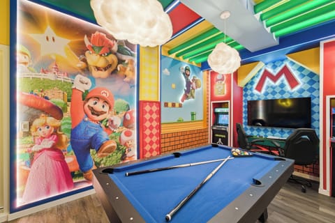Enjoy a colorful Super Mario themed game room with a blue pool table, arcade machines, gaming chairs, a wall-mounted TV, and playful cloud lights, creating a fun space for kids, teens, and adults.