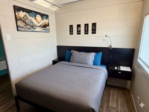 Queen bed framed by mountain landscape art — the calm, dark-mood heart of The Stargazer`s Retreat