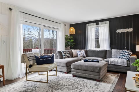 Bright, modern lounge with a cozy sectional and peaceful forest views. 