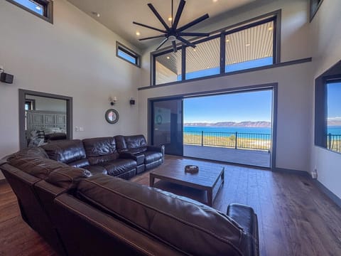 Bright living room with leather sectional and stunning lake‑and‑mountain views through floor‑to‑ceiling window