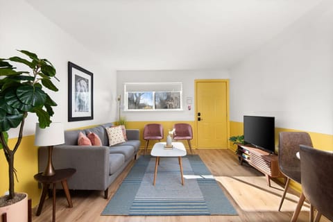 The bright living space features a bold yellow front door and a cheerful, inviting atmosphere.