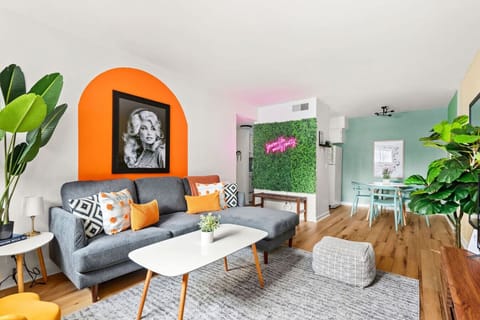 A bold orange arch frames the living room with a warm, earthy palette and a cheerful Dolly Parton print.