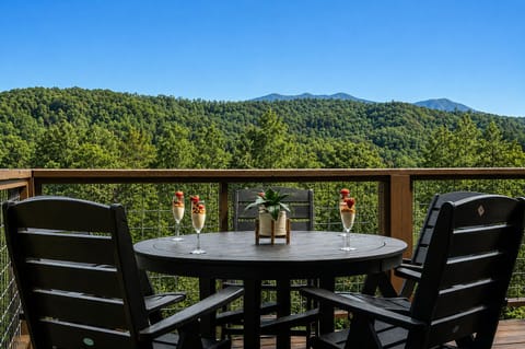 Enjoy your morning coffee or evening drink at a round table on the open balcony, surrounded by peaceful mountain and tree views.