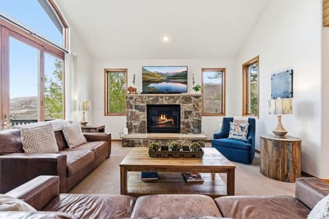 Spacious living room with vaulted ceilings, huge windows, smart TV, and fireplace
