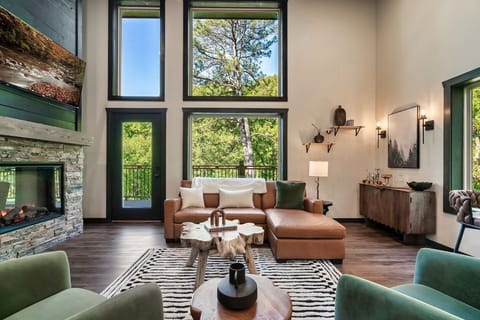 Bright open-concept living room with floor-to-ceiling windows, modern fireplace, and cozy leather sectional. 