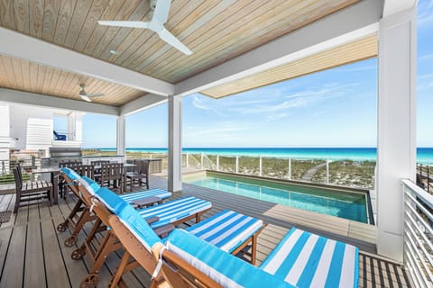 A covered deck features turquoise ocean views, a private pool, outdoor dining, and lounge chairs—ideal for beachside relaxation and entertaining.