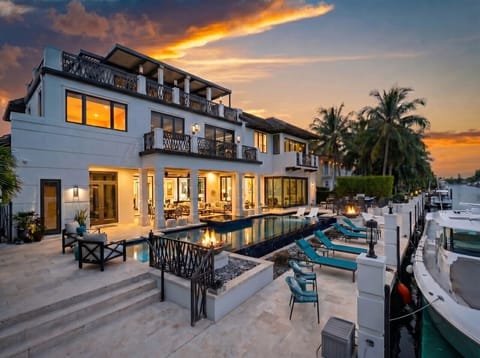 Expansive waterfront property features a sleek private swimming pool, built-in fire pit and extensive patio seating