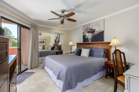 Wood headboard frames king bed with gray quilt, flanked by wooden nightstands and lamps under abstract art.