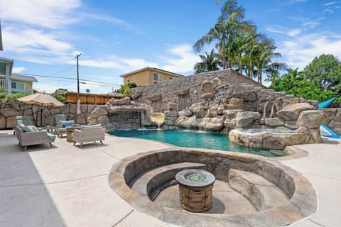 Backyard resort-style pool with rock waterfall, water slide, spa/hot tub, fire pit, and patio seating