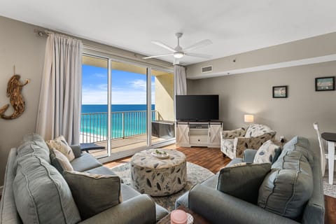 A bright oceanfront living room with comfortable seating, coastal décor, and direct balcony access overlooking the Gulf.