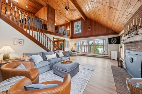 Relax in this lodge-style living room with vaulted ceilings, comfortable seating, and serene lake views just beyond the windows.