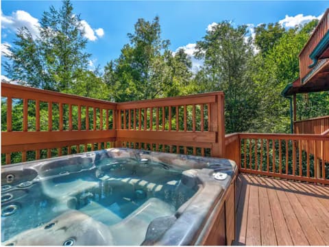 Private outdoor hot tub on the spacious deck surrounded by trees.