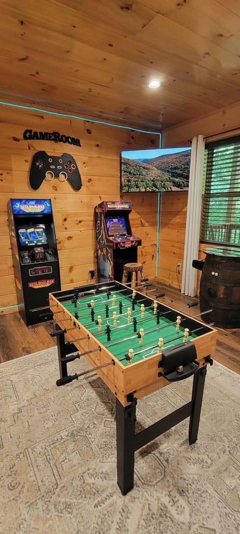Cozy cabin game room with foosball, arcades, and TV fun