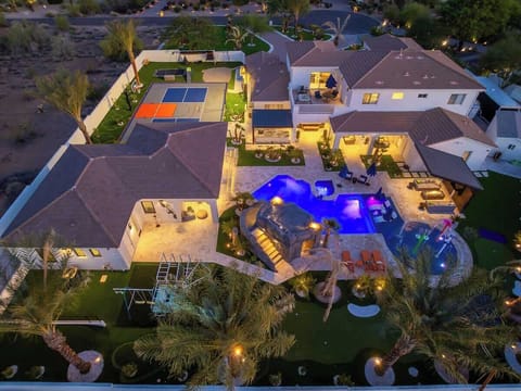 Aerial view of this stunning property showcasing a resort-style pool with spa, basketball court, lush landscaping, and multiple outdoor entertaining areas in a peaceful desert neighborhood setting.
