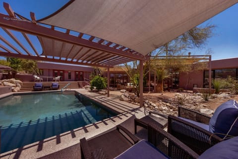 Resort-style backyard with a private pool, shaded lounge areas, and beautiful desert landscaping