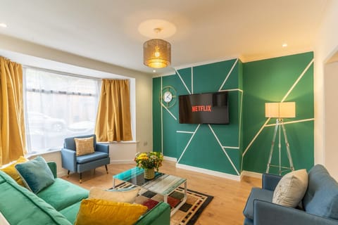 Living room with sofas, an armchair, a coffee table, and a wall-mounted TV.