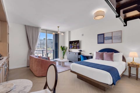 Stylish Wynwood studio featuring a plush king bed, cozy lounge area, dedicated workspace, and balcony access with city views. Smart TV, designer art, and chic furnishings make this your perfect Miami home base.