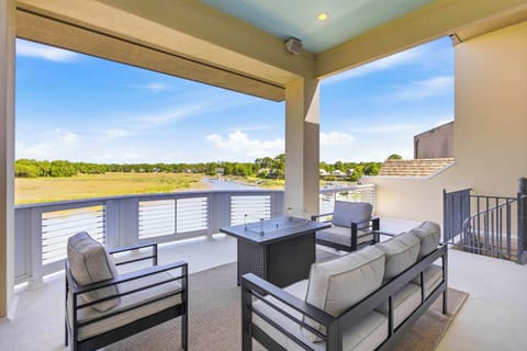Upper deck with a fire pit table, plush outdoor seating, and unobstructed panoramic views of the marsh and waterway.