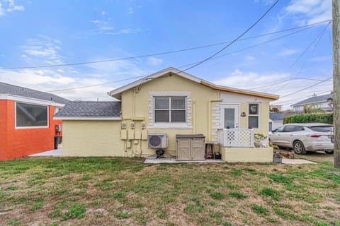 Exterior view of a yellow bungalow with white-trimmed windows, a small porch, and a patchy grass yard.