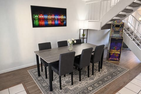 Elegant 8-seat dining room with vintage arcade machine for game-night entertainment