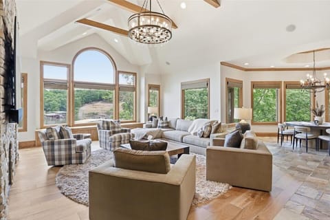 Spacious luxury living room featuring vaulted ceilings, elegant furnishings, large windows, and plenty of natural light for a comfortable group stay.