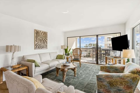 Relaxing Coastal Living Area Featuring Plush Couch and Chairs, a Flat Screen Smart TV, and Expansive Oceanfront Views
