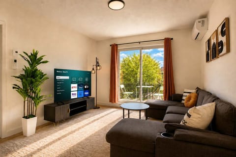 Détendez-vous dans ce salon baigné de soleil, doté d'un grand canapé d'angle confortable, d'une Smart TV avec applications de streaming, de la climatisation et d'une belle vue verdoyante sur le balcon privé.