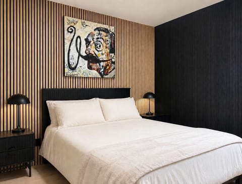 Dormez avec style. Cette chambre magnifiquement aménagée dispose de tables de chevet noires élégantes assorties, de lampes de table dômes modernes et d'une esthétique architecturale unique, parfaite pour un séjour de détente.