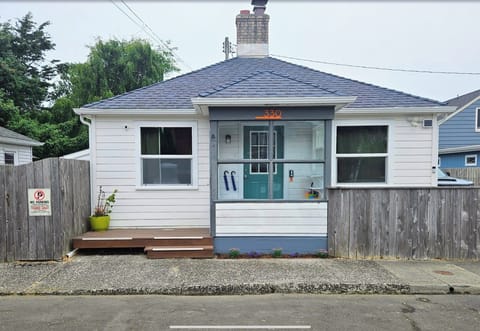 A charming coastal cottage with a welcoming teal door, wooden deck, and peaceful residential setting provides the perfect home base for your getaway.