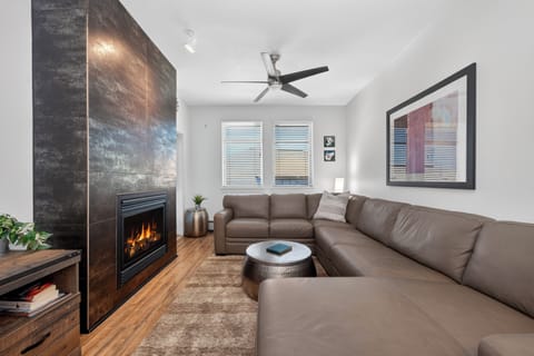 Sink into plush leather seating and feel the warmth of the fireplace glow across this bright, modern living space with vaulted ceilings and natural light.