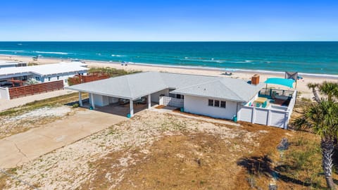 Beachfront property situated directly on pristine sandy shores with turquoise waters and neighboring coastal homes in a quiet beach community.