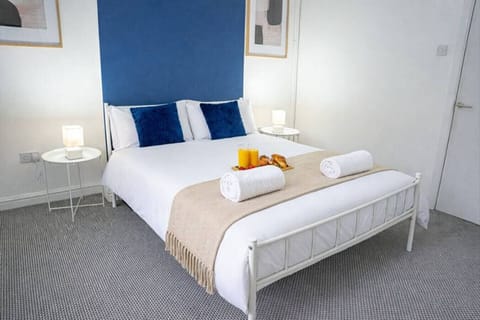 Double bed with bedside lamps, blue cushions, and towels placed on the bed.