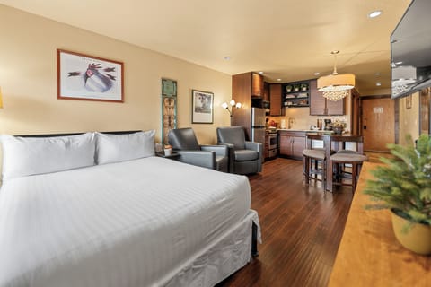 Your open-concept studio blends comfort and convenience, featuring a plush bed, cozy seating, and a well-equipped kitchenette with warm wood cabinetry—all in one welcoming space.