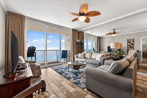 Relax in your spacious living room where tropical ceiling fans and floor-to-ceiling windows frame stunning ocean views.