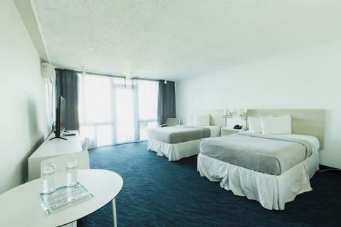Cozy, vintage‑style ESJ Towers bedroom with two comfy full beds, cool A/C, and soft blue carpet, perfect for relaxing after a day on Isla Verde Beach.