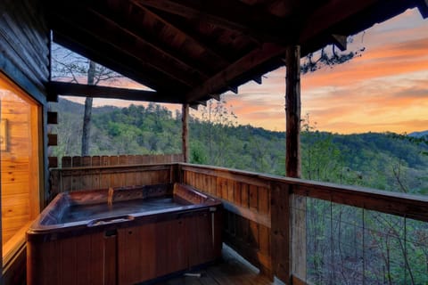Covered cabin deck with a private hot tub, timber beams, and wide open views of the forested hills. (Jack's Cabin)