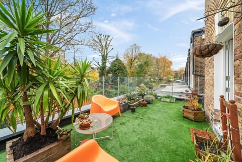Sunny private terrace with lush plants and open treetop views above London.